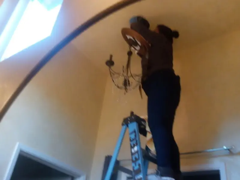 Electrician installing a chandelier in a Verona residence